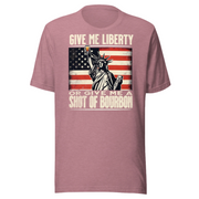 T-shirt with Give Me Liberty or Give Me a Shot of Bourbon text, Statue of Liberty holding a shot glass, and distressed American flag background. Perfect for 4th of July.