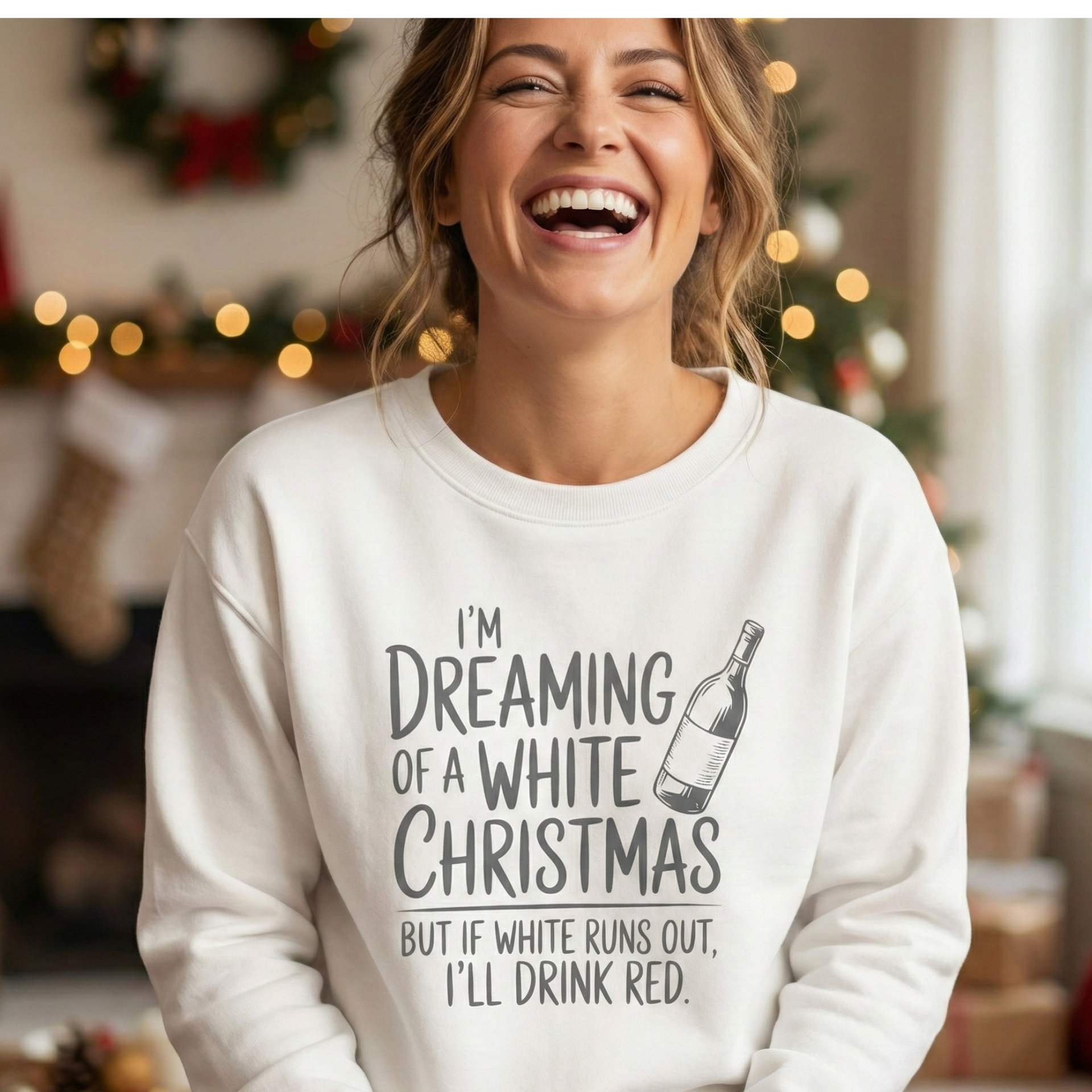 Laughing woman wearing a funny white Christmas sweatshirt for wine lovers featuring the text 'I'm Dreaming of a White Christmas but if white runs out I'll drink red,' perfect for a cozy holiday party outfit.