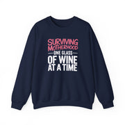 a navy sweatshirt with the phrase 'Surviving Motherhood One Glass of Wine at a Time' funny mother's day, mom life, girls trip design