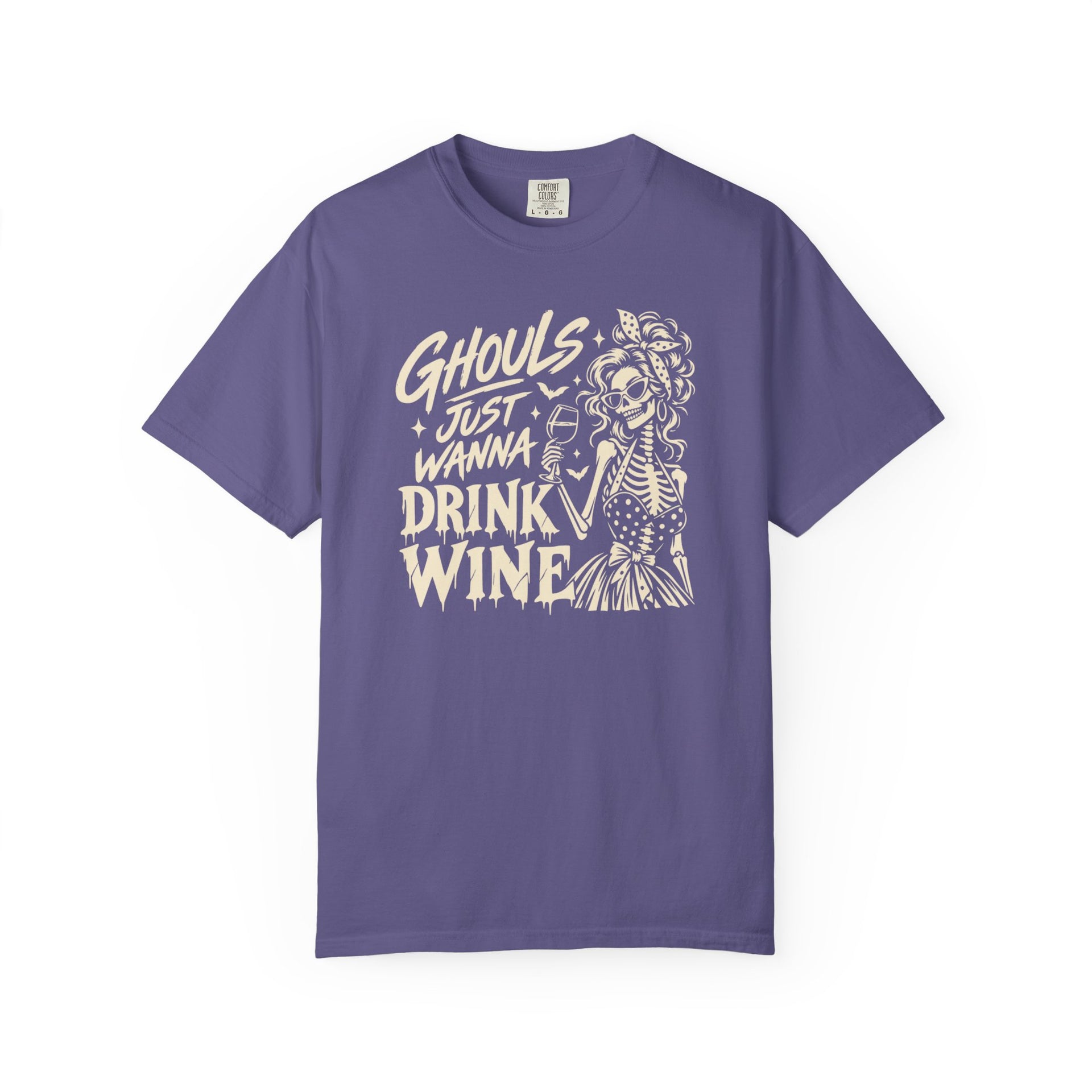 A purple short-sleeve crewneck t-shirt with a cream-colored graphic on the front that reads 'Ghouls Just Wanna Drink Wine' alongside a skeleton illustration, shown against a plain white background.