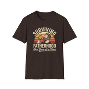 a funny brown t-shirt with the phrase 'Surviving Fatherhood One Beer at a Time" and a retro sunset graphic of a man drinking a beer funny father's day dad gift idea
