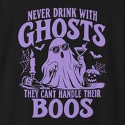 A black short-sleeve crewneck t-shirt with a purple graphic on the front. The graphic features a cartoon ghost holding a cocktail, surrounded by bats, a pumpkin, and spiderwebs, with the text 'NEVER DRINK WITH GHOSTS THEY CAN'T HANDLE THEIR BOOS'.