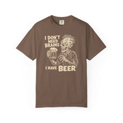 A brown short-sleeve crewneck t-shirt featuring a beige graphic of a zombie holding a beer mug with the text 'I DON'T NEED BRAINS I HAVE BEER'.