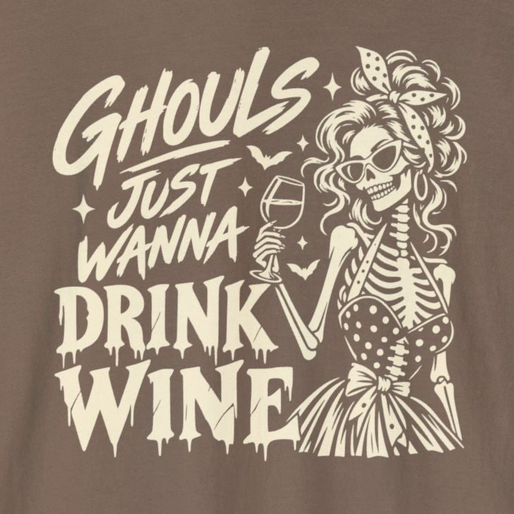 A brown long-sleeve t-shirt with a cream-colored graphic on the front featuring a skeleton woman holding a wine glass and the text 'Ghouls Just Wanna Drink Wine'.