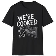 Funny Christmas Short Sleeve Shirt with a gingerbread man holding the oven door open with a sheetpan of gingerbread cookies and the text "We're Cooked" - Black