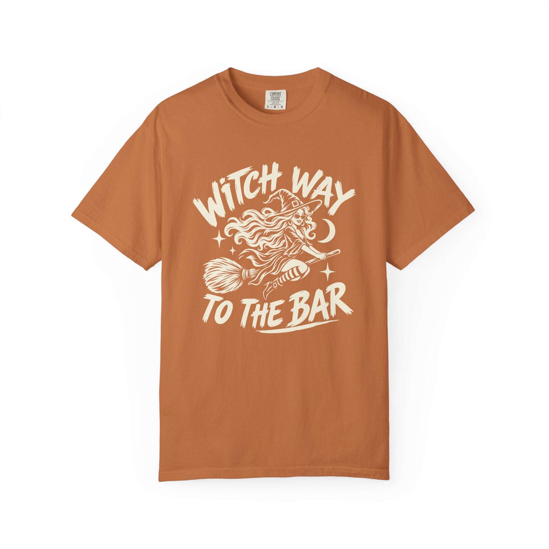 A rust-orange short-sleeve t-shirt with a white graphic print on the front that reads 'WITCH WAY TO THE BAR' around an illustration of a witch riding a broomstick.