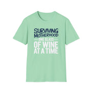 a light green t-shirt with the phrase 'Surviving Motherhood One Glass of Wine at a Time' funny Mother's day, beach vacation, spring break design