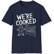 Funny Christmas Short Sleeve Shirt with a gingerbread man holding the oven door open with a sheet pan of gingerbread cookies and the text "We're Cooked" - Navy Blue