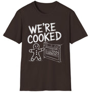 Funny Christmas Short Sleeve Shirt with a gingerbread man holding the oven door open with a sheetpan of gingerbread cookies and the text "We're Cooked" - Dark Chocolate