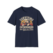 a funny navy t-shirt with the phrase 'Surviving Fatherhood One Beer at a Time" and a retro sunset graphic of a man drinking a beer funny father's day dad gift idea