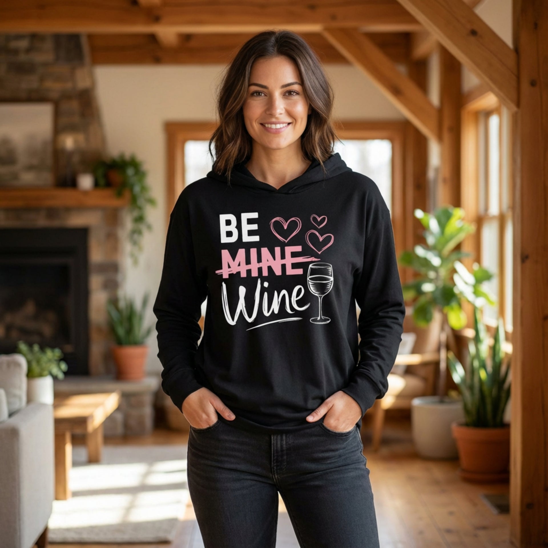 brunette model wearing featherweight hoodie with the phrase "Be Mine". Mine is crossed out and Wine is written underneath. minimalist wine glass and heart graphics complete the design
