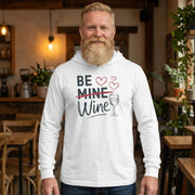 blonde bearded male model wearing white  featherweight hoodie with the phrase "Be Mine". Mine is crossed out and Wine is written underneath. minimalist wine glass and heart graphics complete the design
