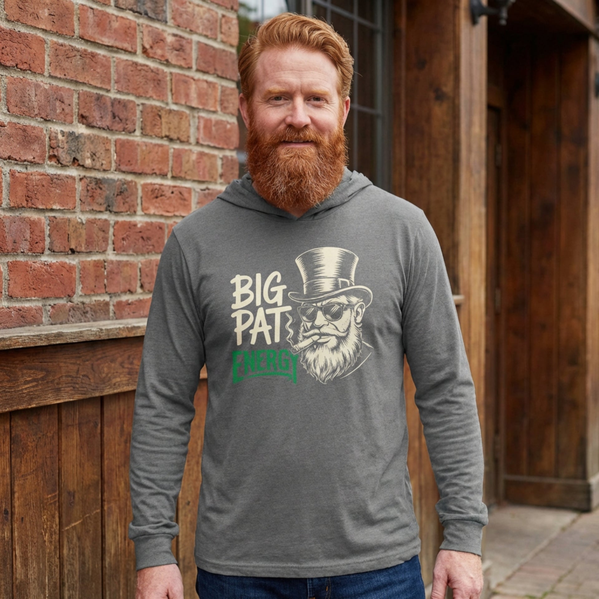 red headed man wearing a grey  lightweight St Patricks  Day hoodie with the Phrase “Big Pat Energy”  with a leprechaun smoking a cigar
