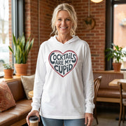 blonde female model wearing white  featherweight hoodie with the phrase "Cocktails are my cupid".  A minimalist valentine heart outline surrounds the phrase to complete the design
