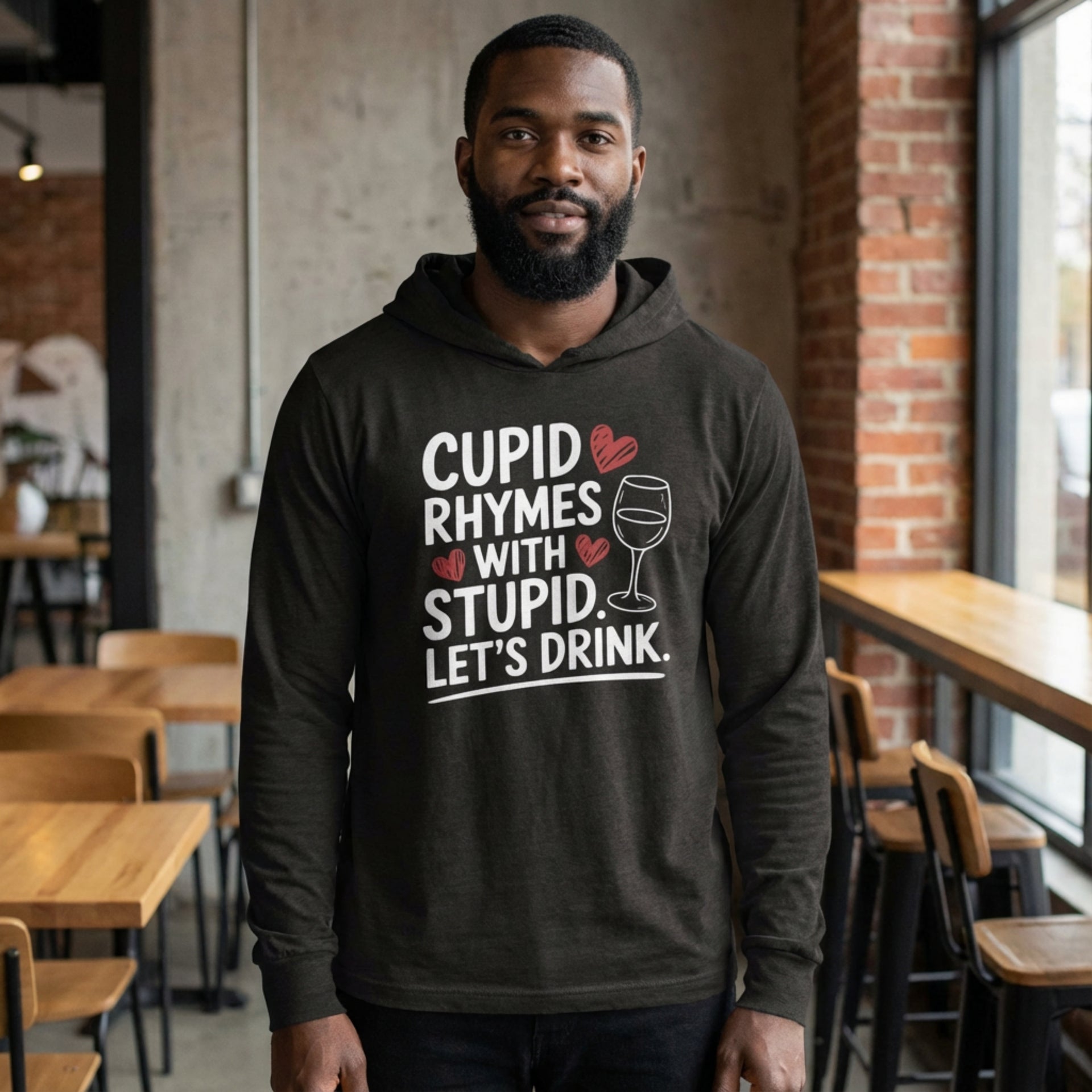 black male model wearing black featherweight hoodie with the phrase "Cupid Rhymes With Stupid Let's Drink" with a minimalist sketched wine glass and valentine's hearts to complete the design

