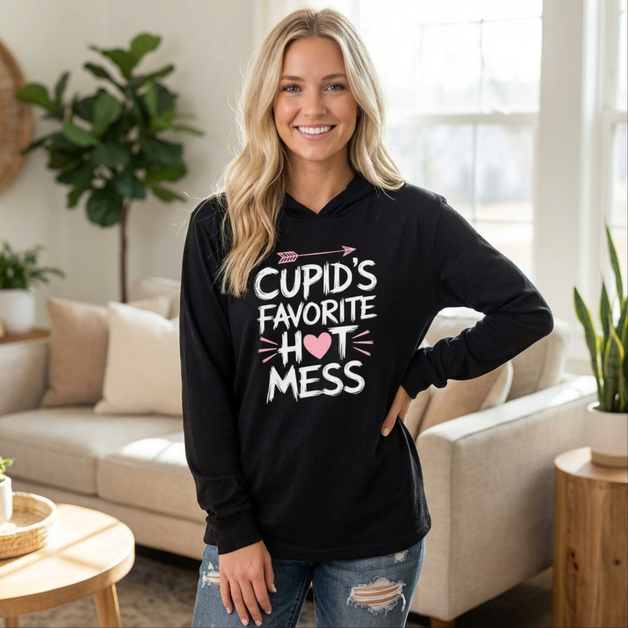 blond woman wearing black lightweight valentine's day hoodie with the Phrase “cupid’s favorite hot mess”  with valentines hearts and cupid’s arrow
