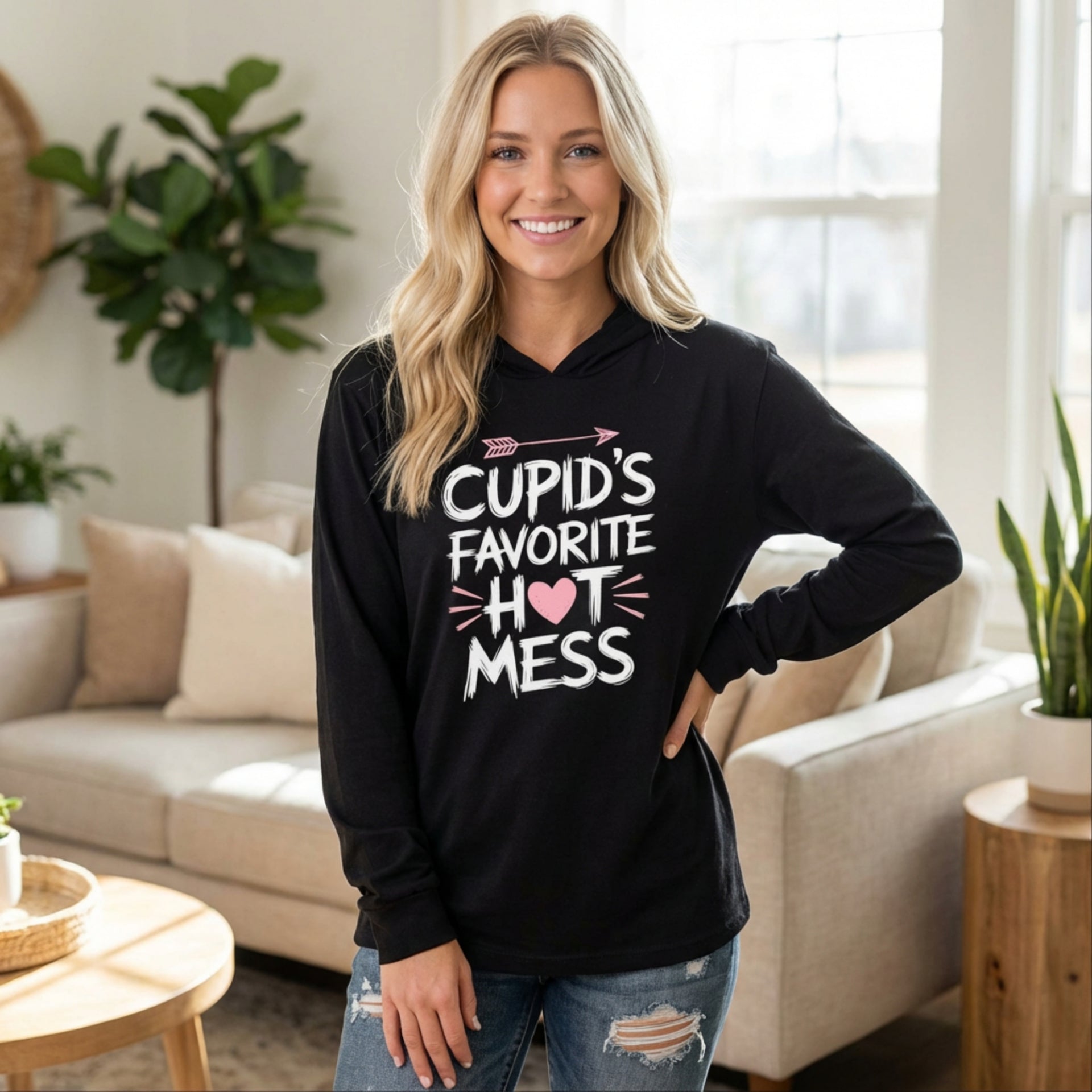 blond woman wearing black lightweight valentine's day hoodie with the Phrase “cupid’s favorite hot mess”  with valentines hearts and cupid’s arrow
