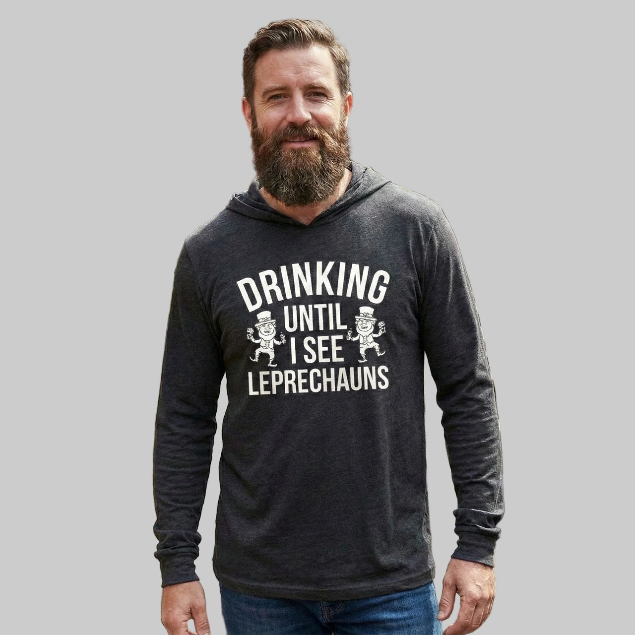 brunette male wearing a black lightweight St Patricks  Day hoodie with the Phrase “Drinking Until I See Leprechauns”  with a leprechaun to complete the design