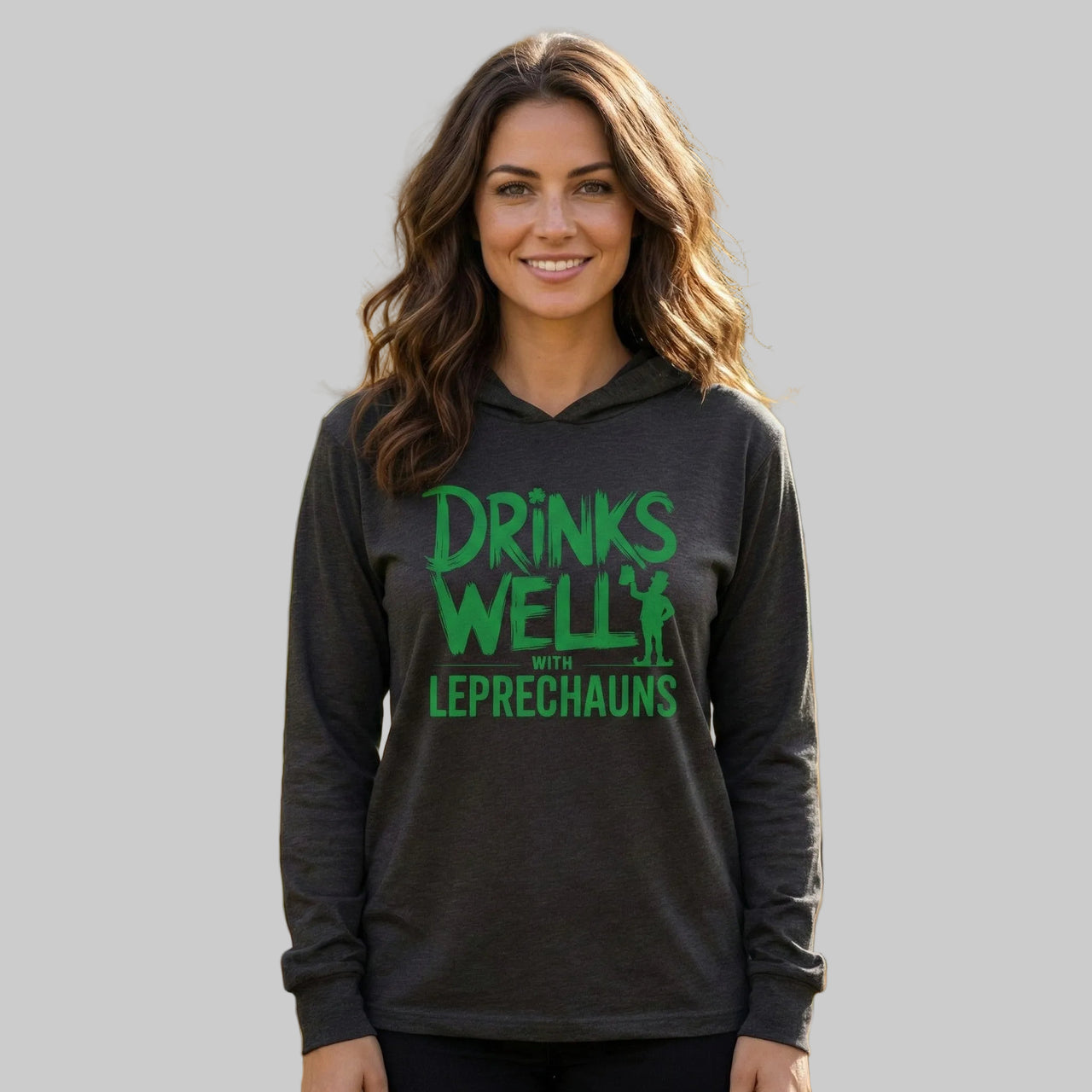 brunette woman wearing a black lightweight St Patricks  Day hoodie with the Phrase “Drinks Well With Leprechauns”  with a leprechaun to complete the design