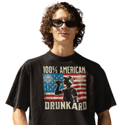 4th of July T-shirt with '100% American Drunkard' text, man drinking a bottle of beer wearing a trucker hat, and distressed American flag background