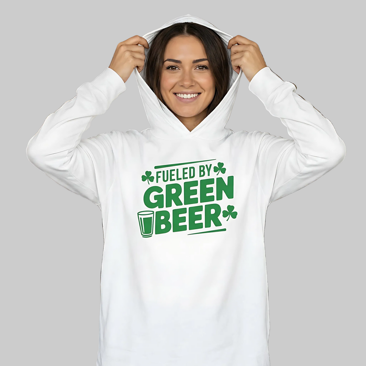 brunette woman wearing a white lightweight St Patricks  Day hoodie with the Phrase “fueled by green beer”  with a shamrocks to complete the design