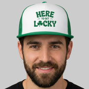 Man wearing a white and green cap with 'Here to Get Lucky' text on a gray background
