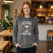 redheaded female model wearing Gray featherweight hoodie with the phrase “I don’t need a valentine I need a cocktail” with an ink sketched wine glass and sketched valentine hearts to  complete the design