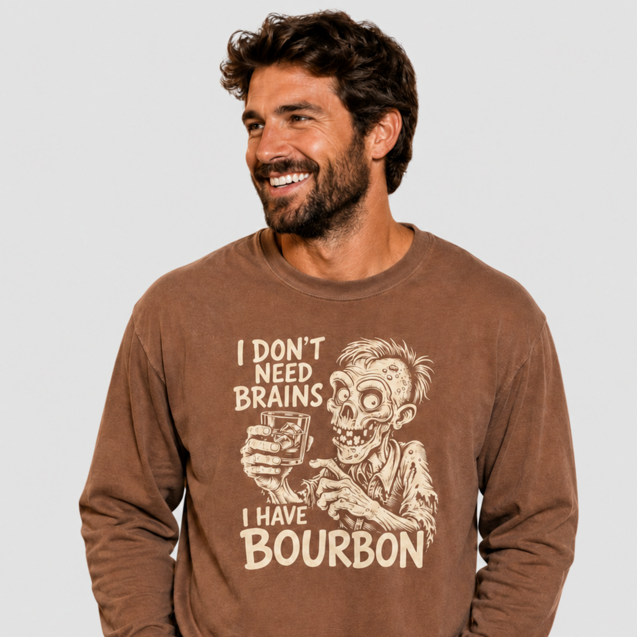 A man wearing a brown long-sleeve graphic sweatshirt with a beige zombie holding a glass and the text 'I DON'T NEED BRAINS I HAVE BOURBON'.