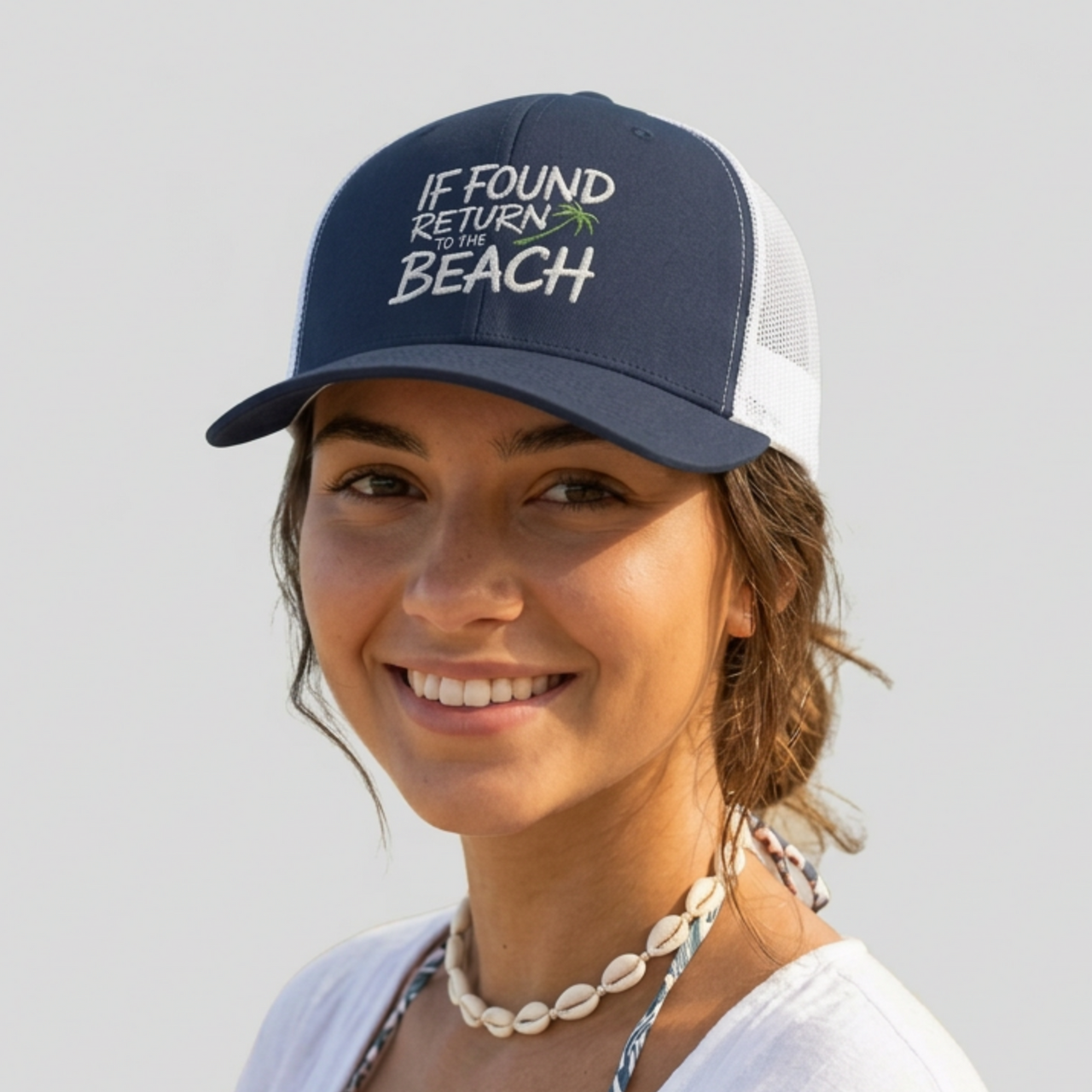 Woman wearing a navy and white trucker hat with the phrase 'If Found Return to the Beach' funny Spring break, girls trip, beach trip, summer vacation, guys trip, bachelor or bachelorette party design