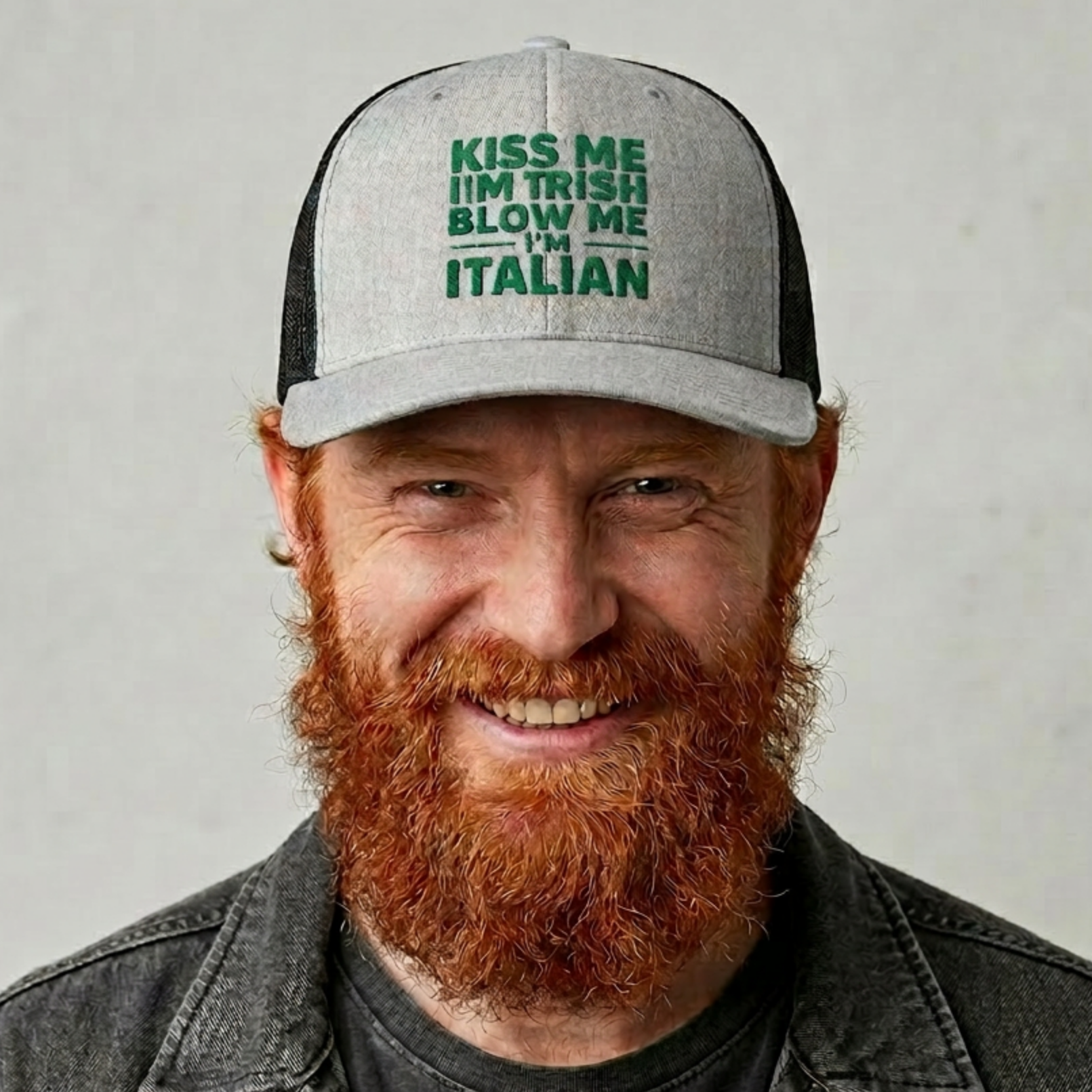 Man wearing a gray and black curved bill trucker hat with the text 'Kiss me I'm Irish, blow me Italian' funny st patricls day pub crawl design