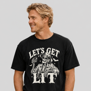 A man wearing a black graphic t-shirt with a white skeleton and 'LET'S GET LIT' print, paired with khaki pants, against a solid gray background.