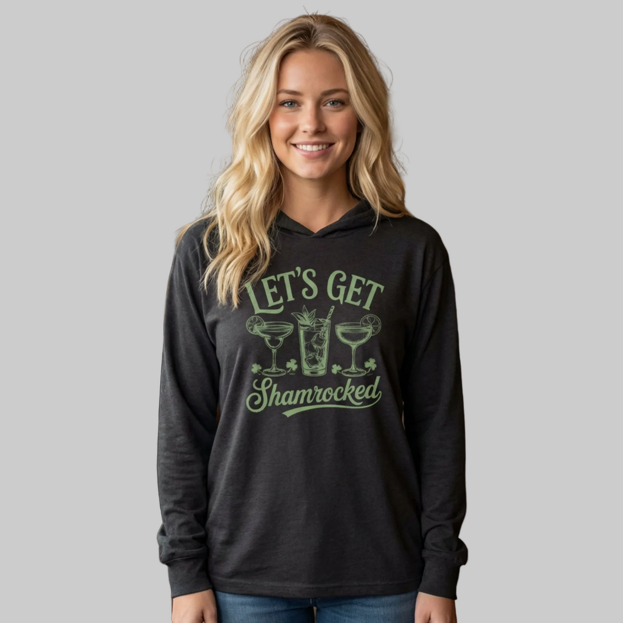 Woman wearing a black hoodie with 'Let's Get Shamrocked' text and cocktail graphics on a gray background