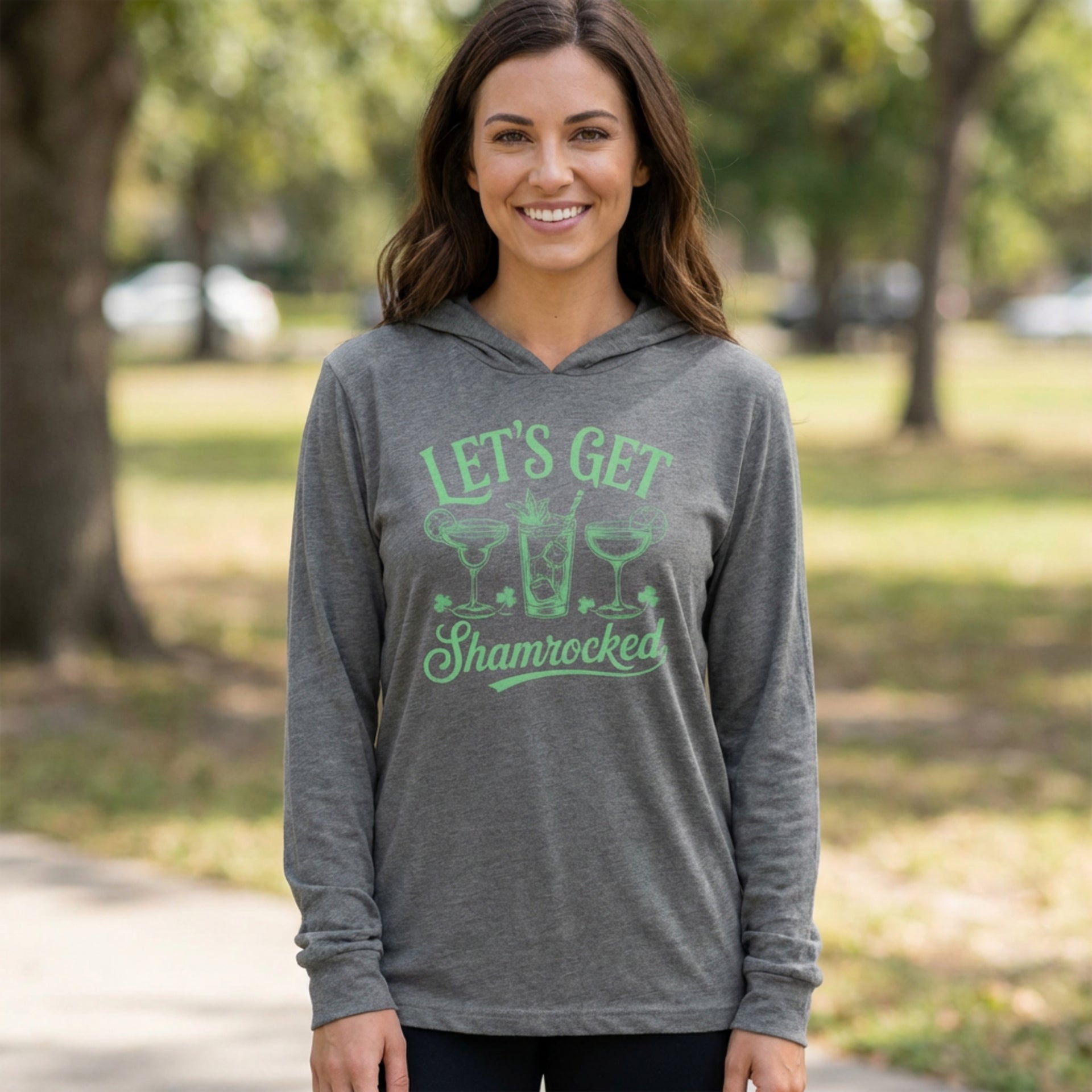 brunette female wearing a gray  lightweight St Patricks  Day hoodie with the Phrase “Lets Get Shamrocked”  with a leprechaun smoking a cigar
