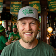 man wearing a gray and black curved bill trucker hat with 'Most Likely to Irish Goodbye' text funny st patricks day pub crawl design