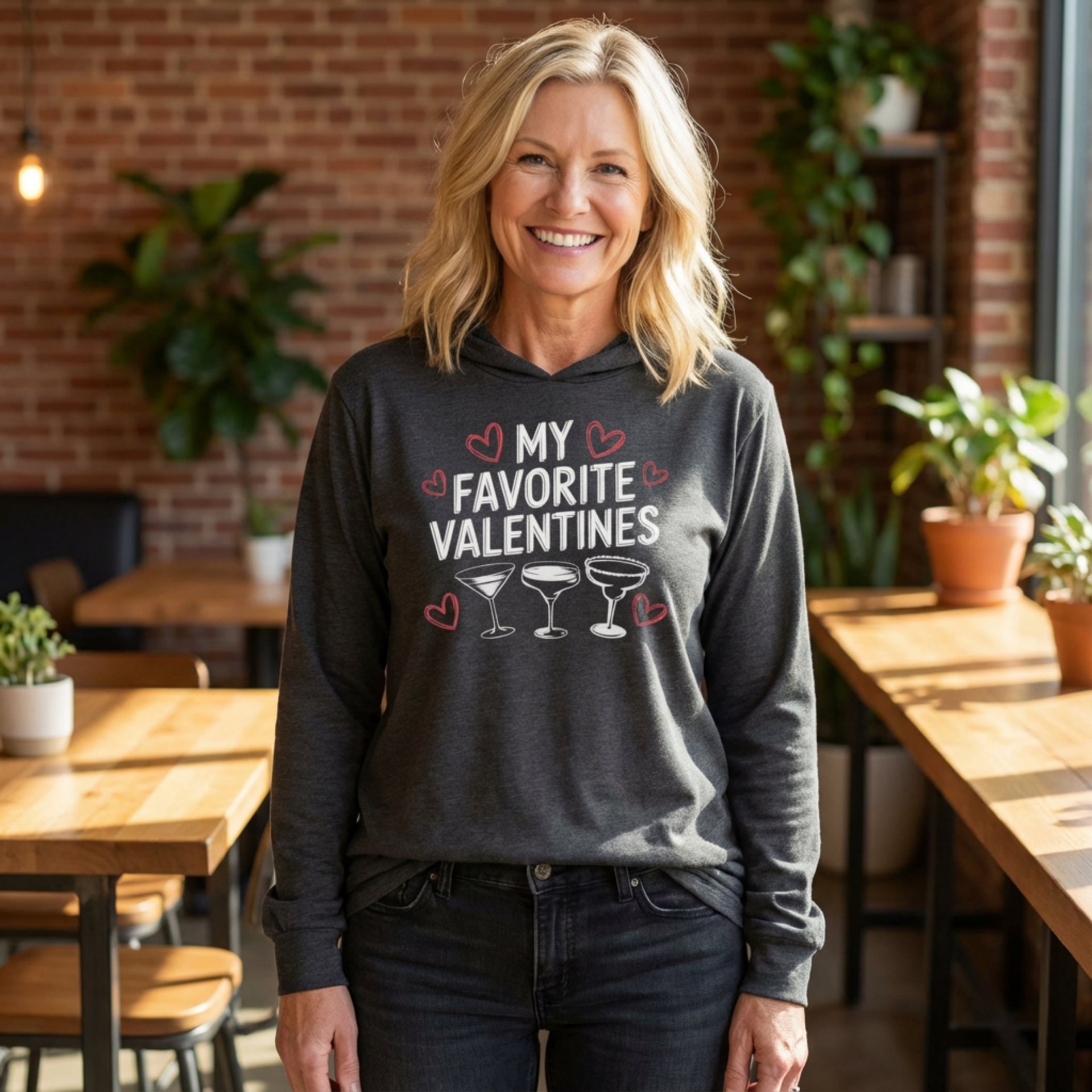 blonde female model wearing featherweight hoodie with the phrase "My Favorite Valentines".  Below the Phrase are three cocktail glasses. Minimalist Valentines Heart outlines surround the the phrase to complete the design
