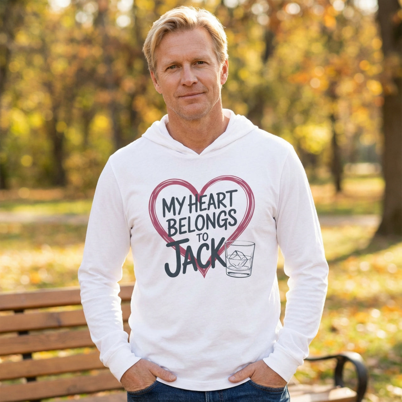 blonde man wearing a white featherweight valentine's day hoodie with the Phrase “my heart belongs to jack” surrounded by a  sketched valentines heart and a bourbon glass
