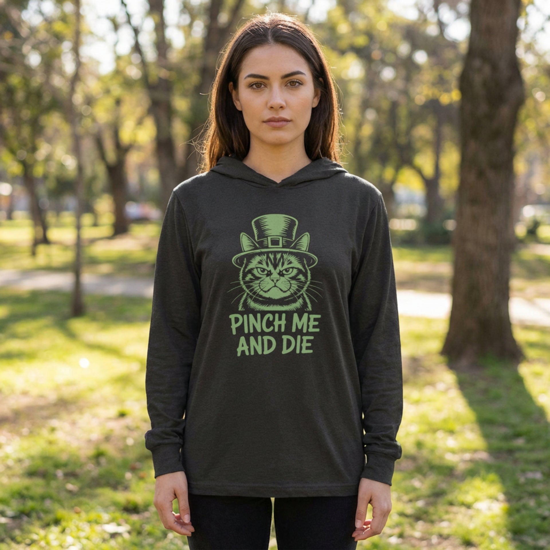 Person wearing a black hoodie with a green graphic and text in a park