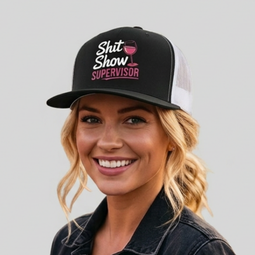 Woman wearing a black and white premium flat bill trucker hat with the phrase SHit Show Supervisor funny girls trip, beach vacation, spring break, summer vacations, lake days design