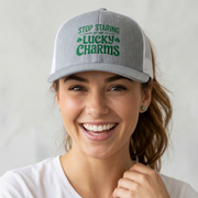 Woman wearing a gray and white curved trucker hat with the phrase Stop Staring at My Lucky Charms funny St Patricks Day pub crawl or parade design