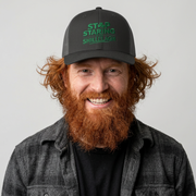 Man wearing a black and gray curved trucker hat with the phrase "Stop Staring at my Shillelagh" funny St Patricks Day pub crawl or parade design