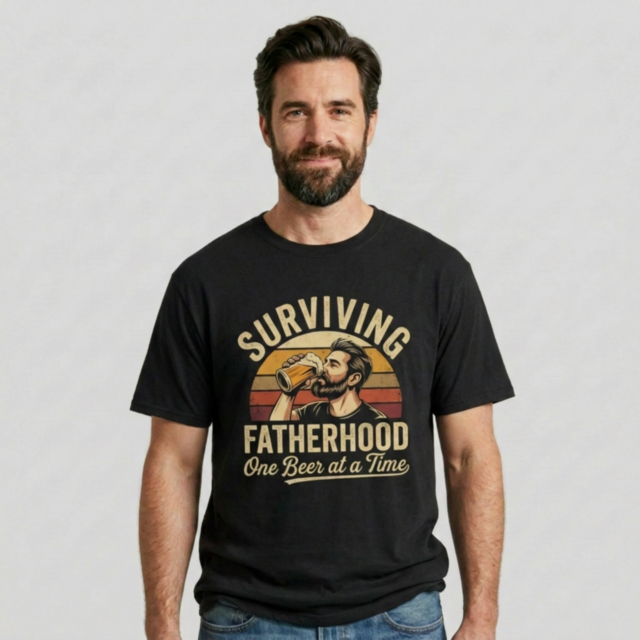 Man wearing a funny black t-shirt with the phrase 'Surviving Fatherhood One Beer at a Time" and a retro sunset graphic of a man drinking a beer funny father's day dad gift idea