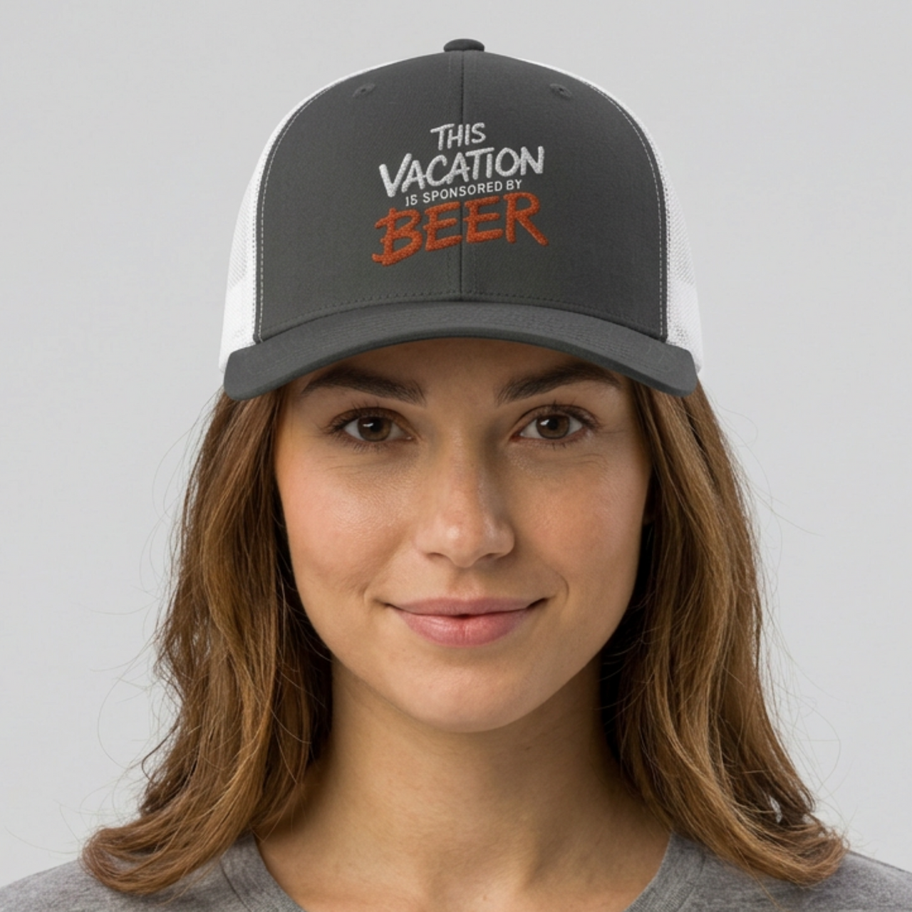 Woman wearing a gray and white embroidered trucker cap  with text 'This vacation is sponsored by beer' funny spring break, beach vacation, lake season design
