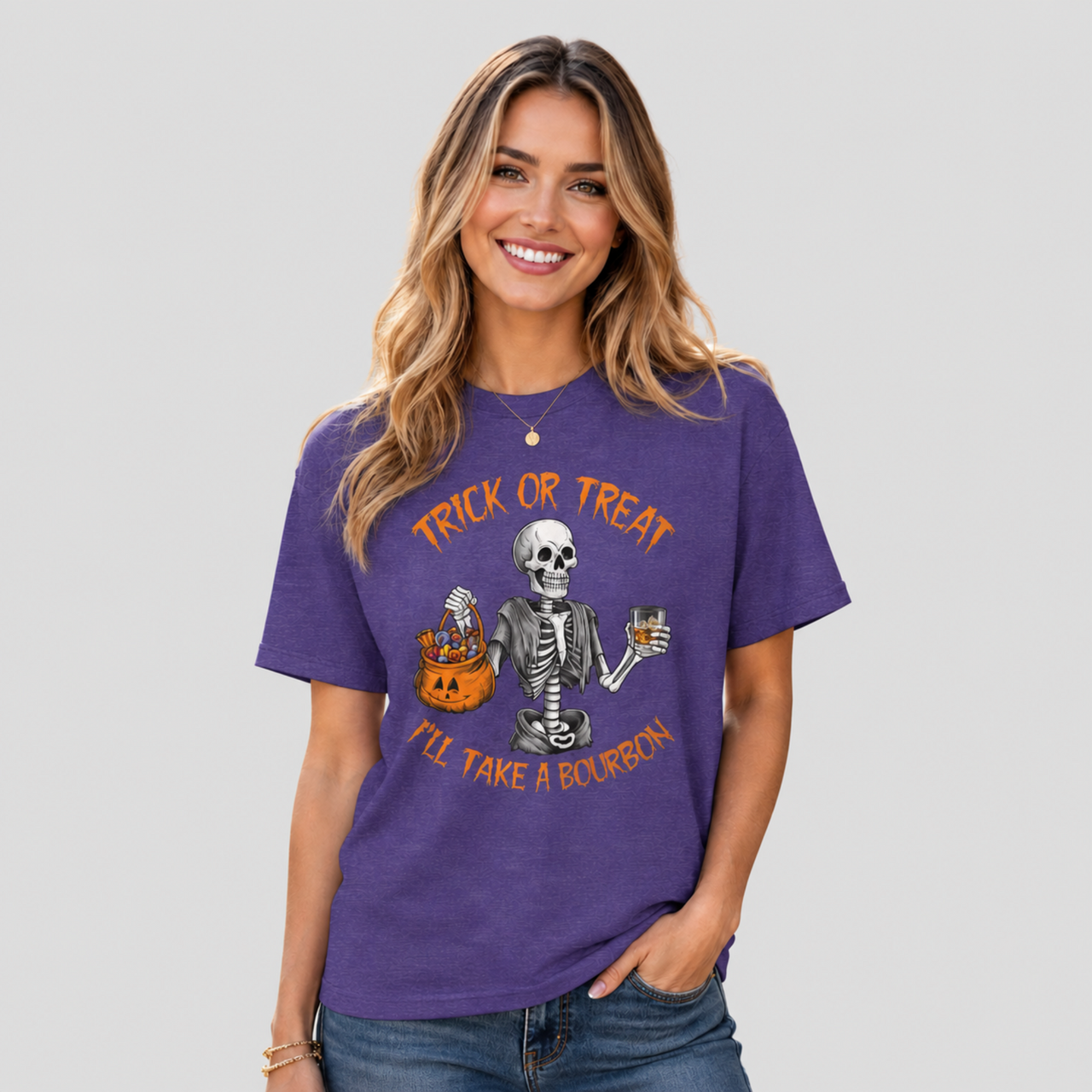 A woman wearing a purple short-sleeve graphic t-shirt with a Halloween design featuring a skeleton, a jack-o'-lantern, and orange text that reads 'TRICK OR TREAT I'LL TAKE A BOURBON'.