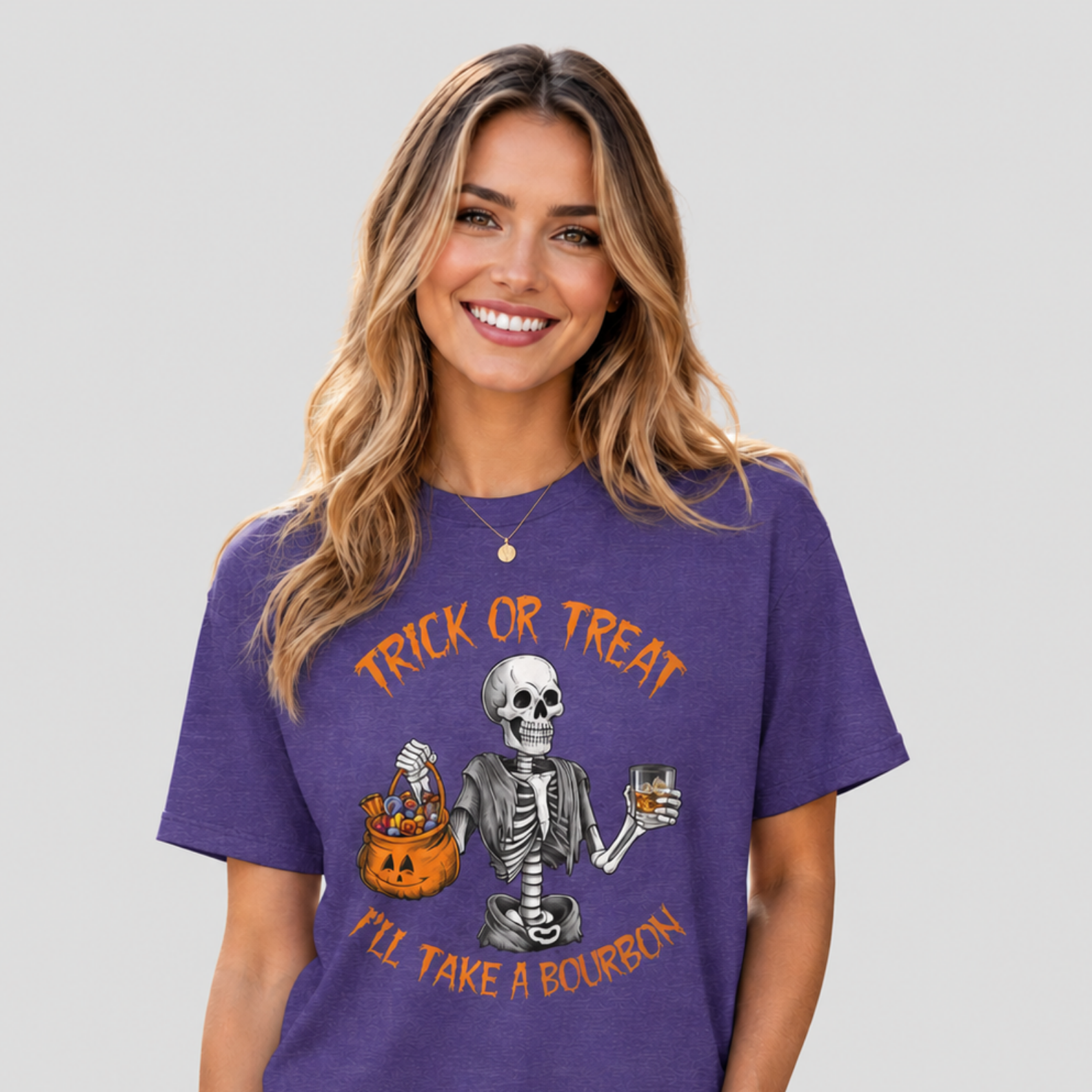 A woman wearing a purple short-sleeve graphic t-shirt with a Halloween design featuring a skeleton, a jack-o'-lantern, and orange text that reads 'TRICK OR TREAT I'LL TAKE A BOURBON'.