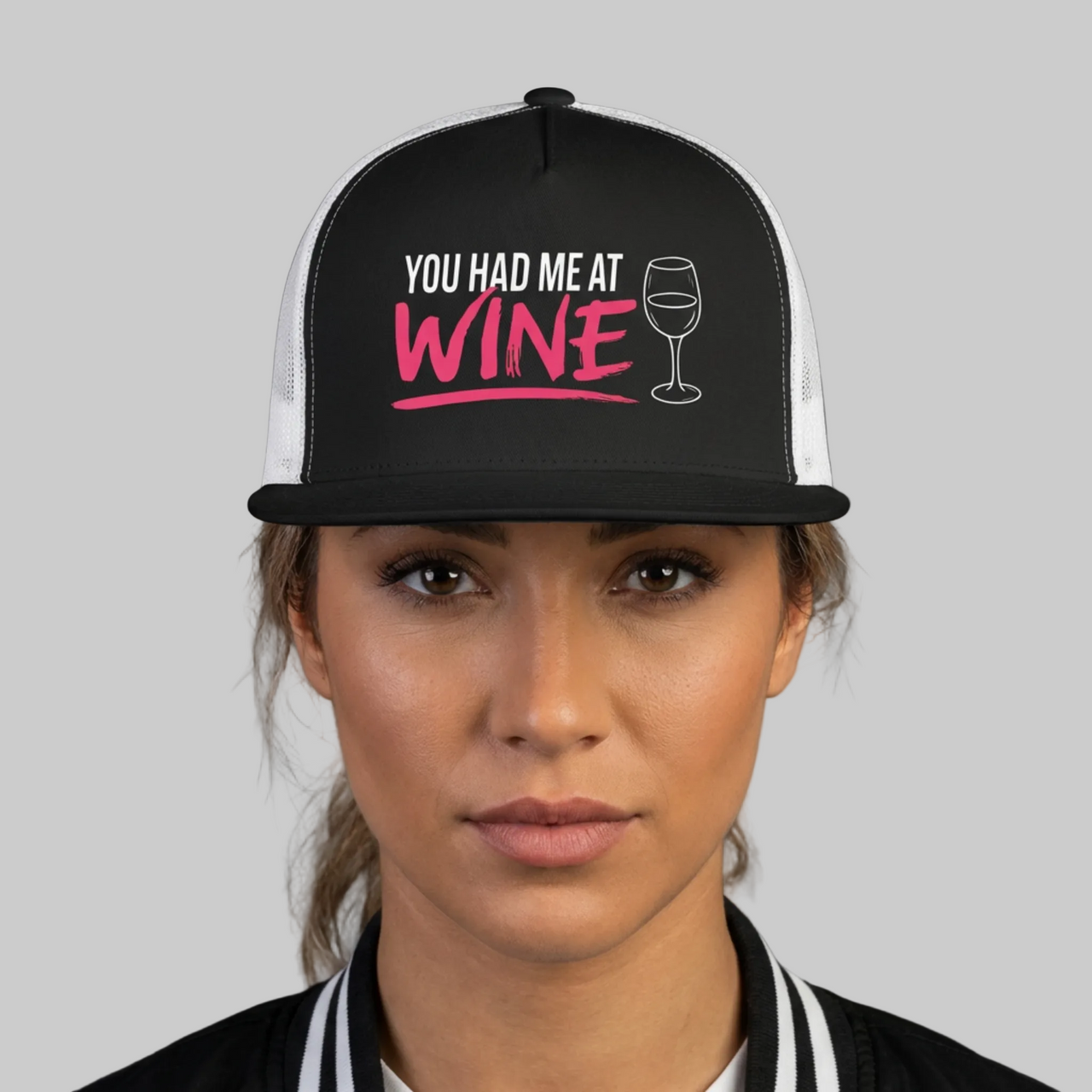 Person wearing a black and white cap with 'You Had Me at Wine' text on a gray background