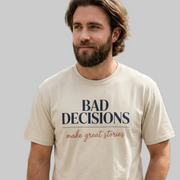 Man wearing a beige t-shirt with text 'Bad decisions make great stories' funny spring break, guys trip, girls trip, beach vacation, bachelor party, bachelorette party design