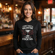 brunette female model wearing black featherweight hoodie with the phrase “I don’t need a valentine I need a cocktail” with an ink sketched wine glass and sketched valentine hearts to  complete the design