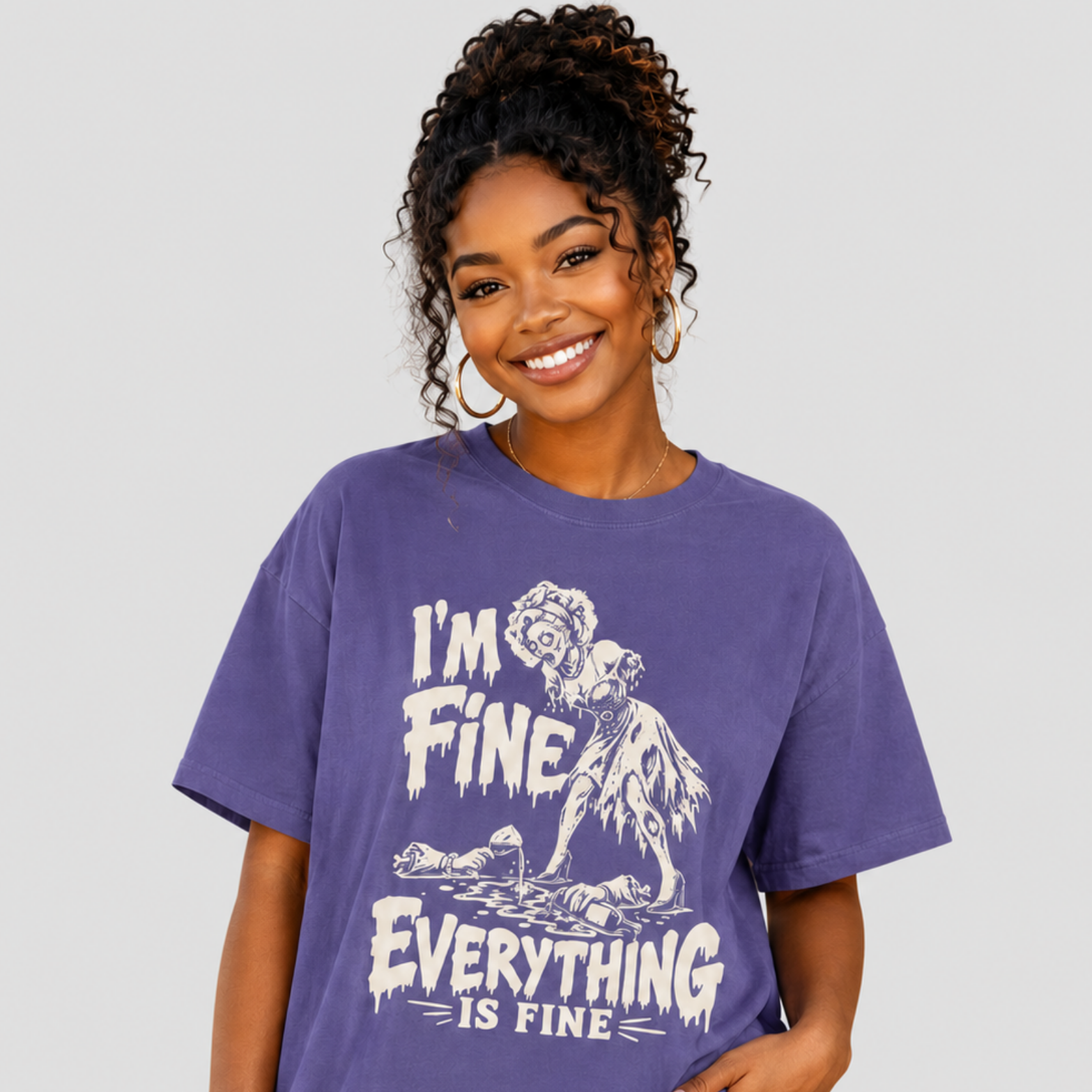 A woman modeling a purple graphic t-shirt with a white distressed print that reads 'I'M FINE EVERYTHING IS FINE' and shows a zombie graphic, against a solid light gray background.