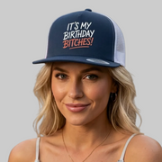 Woman wearing a cap with text and holding a cocktail, against a gray background