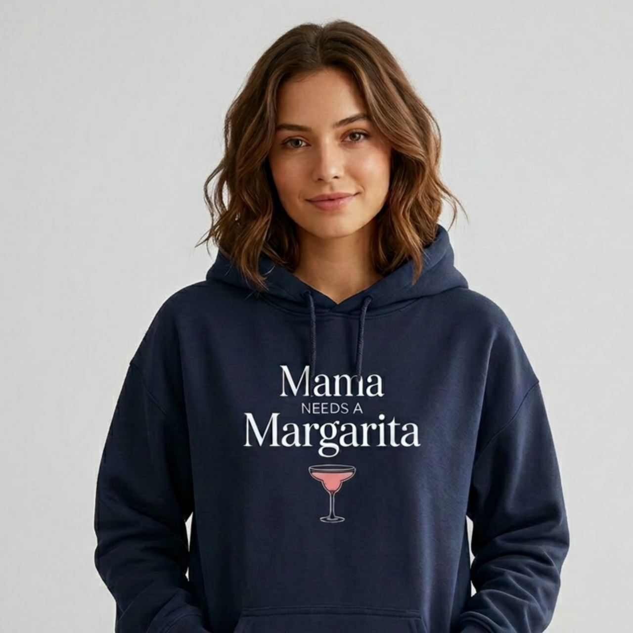 Woman wearing a navy hoodie with 'Mania Needs a Margarita' text and a cocktail graphic funny mother's day, girls trips, beach trips, mom life design